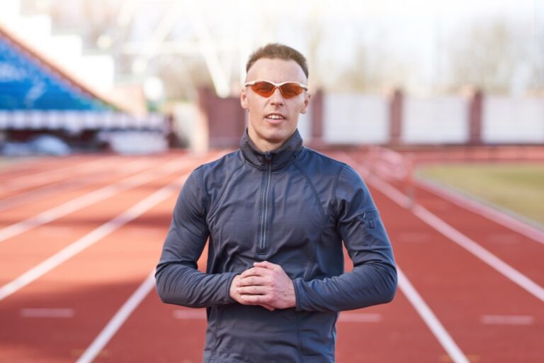 Uomo Atletico In Posa Sulla Pista Di Atletica Con Occhiali Da Corsa